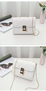 Close-up of white quilted PU leather crossbody bag with gold chain and metal lock