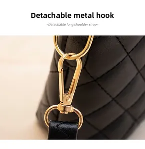 Detail of detachable golden hardware hook and quilted leather strap on black tote bag