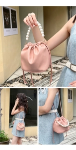 Detail of pink lychee textured bucket bag with pearl handle and ribbon charm