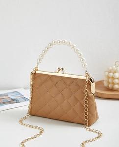 Quilted latte leather wallet with pearl handle and golden chain on a decorative tray