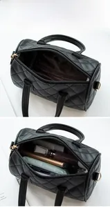 Detail showing high-capacity interior of black quilted PU leather boston bag with gold hardware