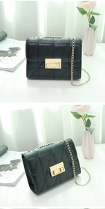 Detail of black quilted crossbody bag with gold chain strap and metal turn-lock closure