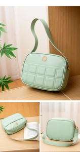 Macro detail of mint green quilted shoulder bag with golden embossed emblem and zipper
