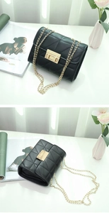 Detailed view of the black quilted chain bag featuring a gold metal lock and leather texture