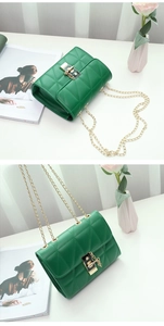 Detail of green quilted crossbody bag with golden chain strap and square metal clasp
