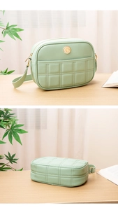 Close-up of mint green quilted handbag with golden logo and square embroidery details