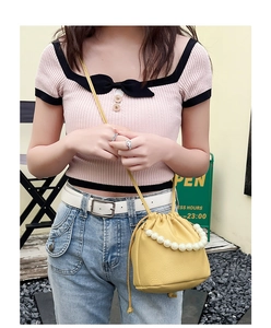 Detail showing yellow lychee texture bucket bag with pearl handle and drawstring close