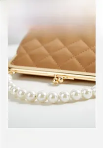 Detail of caramel quilted wallet featuring pearl handle and golden metal clasp closure