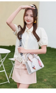 Detail of white quilted crossbody bag with floral silk scarf and letter printed strap