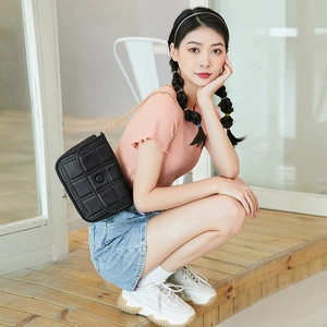 Borsa a tracolla trapuntata nera con catena dorata mostrata su una modella di moda