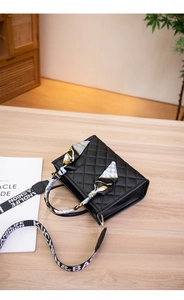 Detail of black quilted handbag with silk scarf handle and wide patterned shoulder strap