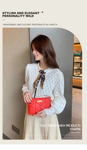 Detail of red quilted cross-body bag featuring gold chain strap on female model