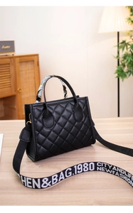 Detail of black quilted shoulder bag featuring gold hardware and printed silk scarf handle