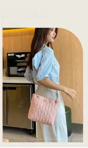 Asian woman carrying a pink quilted crossbody bucket bag with gold chain strap.