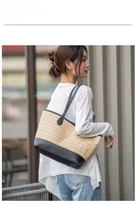 Dettaglio della borsa tote in paglia intrecciata con fondo e tracolle in pelle nera su modella