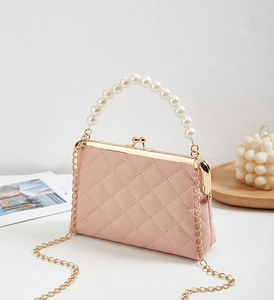 Detailed close-up of pink quilted leather bag with pearl handle and metal chain