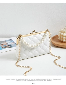 Detail of quilted white pearl handbag with gold chain strap and elegant pearl handle