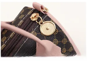 Gros plan sur la fermeture éclair dorée et les finitions en cuir rose du sac boston