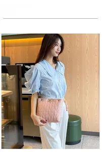 Pink quilted shoulder bag with gold twist lock and metal chain strap worn by a model