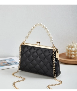 Detail of black quilted leather handbag with pearl handle and golden metal frame clasp