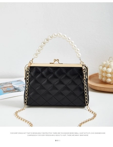 Detail of black quilted handbag with pearl top handle and vintage gold kiss-lock closure