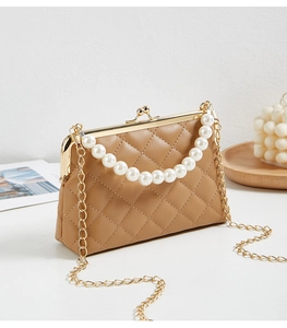 Quilted light brown leather handbag with pearl handle and golden chain on a table