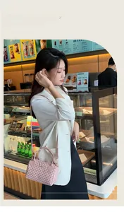 Pink cylinder handbag with butterfly detail shown in a lifestyle coffee shop setting