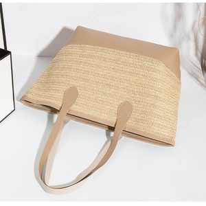 Dettaglio della borsa tote in paglia intrecciata con finiture in pelle marrone