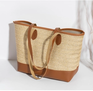 Dettaglio borsa tote in paglia intrecciata con finiture in ecopelle marrone e manici in tessuto