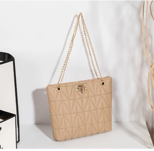 Detail of beige quilted tote bag featuring geometric patterns and gold chain strap