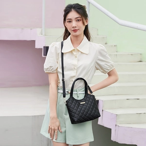 Quilted tote bag in black with gold hardware shown as a crossbody by a model outdoors