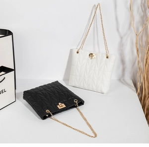 Detail of geometric quilted mini bucket bag with gold leaf lock and chain strap