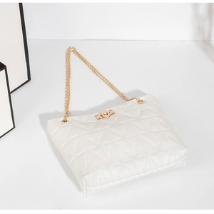 Detail view of white quilted bucket bag with gold chain strap and elegant turn-lock closure