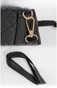 Detailed view of black quilted shell bag featuring gold hardware and stitched handle