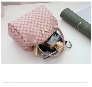 Pink printed leather handbag detail showing interior storage with makeup items