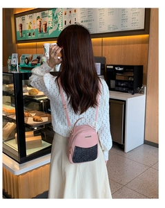 Lifestyle shot of a mini pink leather backpack with black sequins in a cozy cafe setting