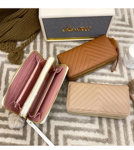 Detail view of quilted women wallets with dual zippers and plush pom-pom charms