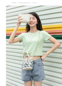 Détail d'un mini sac seau en PVC transparent avec motif marguerites et chaîne dorée