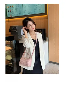 Pink Boston bag with floral print and adjustable strap worn by model in a cafe
