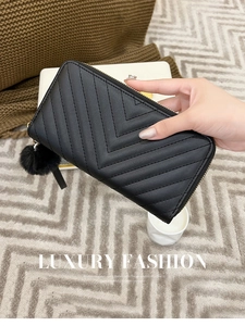 Detail of black quilted leather wallet with gold zipper and stylish faux fur pom pom charm