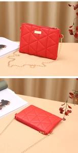 Detail view of red quilted PU leather bag with golden chain and metal plate accents
