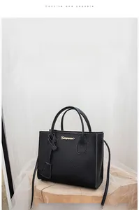 Detail of black lychee grain leather tote bag with gold logo and detachable strap