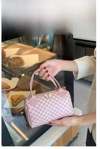 Close-up of pink Boston handbag with dotted patterns and butterfly ornament detail