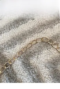 Detail of elegant gold metal chain shoulder strap with oval links for luxury handbag