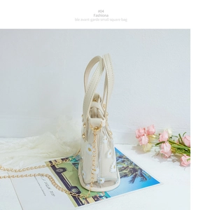 Détail du sac à main en PVC transparent avec imprimés marguerites et bandoulière dorée