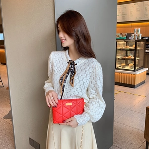 Red quilted crossbody bag with gold chain strap shown in a cafe setting with model