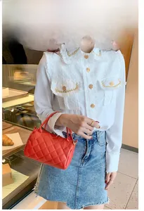 Détail d'un petit sac polochon rouge matelassé avec poignée en cuir et zip métallique