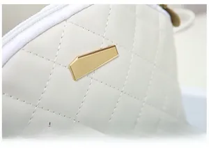 Dettaglio della chiusura geometrica dorata sulla borsa trapuntata beige da donna