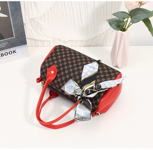 Détail du sac Boston avec motif vintage, foulard en soie et poignées rouges contrastées