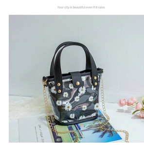 Détail du sac à main transparent à motif marguerites avec garniture en cuir noir et chaîne
